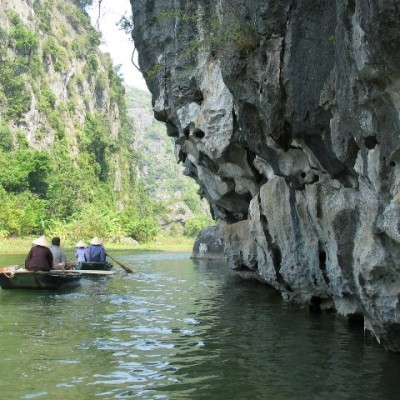 Promenade en barque à travers les roches karstiques sur l'eau à Tam Coc